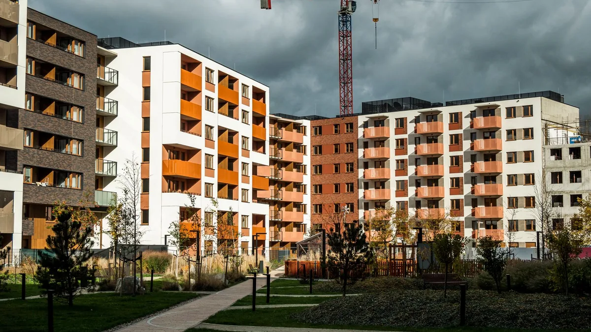 Nowe bloki mieszkalne z żurawiem budowlanym nad częścią osiedla.