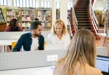 Na co zwrócić uwagę wybierając kierunek studiów prawniczych za granicą Międzynarodowa grupa studentów pracuje przy laptopach w bibliotece kampusu.